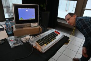 Un visiteur penché sur un Commodore qui fait tourner un jeu