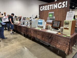 Une longue table d'ordinateurs sous une enseigne « Greetings! »